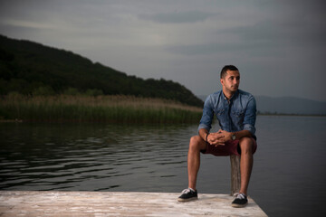 Fototapeta premium Fashion portrait of young man in denim shirt poses over wall with contrast shadows