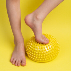 children's feet with a yellow balancer on a light yellow background, treatment and prevention of...
