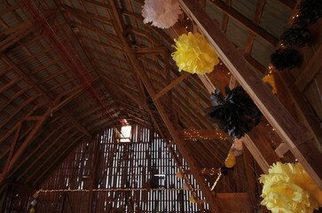 Yellow Black and White Tissue Pompom Decorations Dress up the Inside of a Rustic Barn for a Dance
