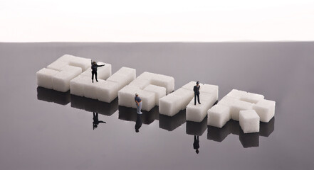 Sugar cubes arranged to spell 'SUGAR' with miniature model police officers stood on top directly a...