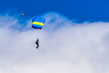 Sky diving parachutist decending against a blue sky