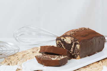 Chocolate marble loaf cake with chocolate glaze. On white cafe table.