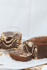 Chocolate marble loaf cake with chocolate glaze. On white cafe table.