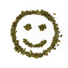green pumpkin seeds in the shape of smiling face on white background, healthy eating concept, food for breakfast, top view, close up