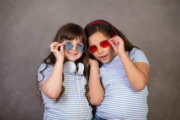 Portrait of two cute, charming, cute little girls who are happy and having fun in the studio on a gray background