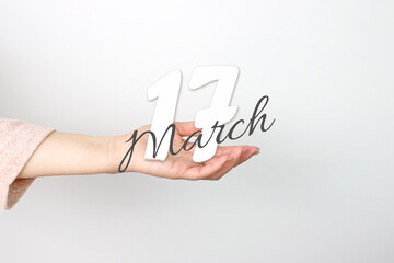 March 17th. Day 17 of month, Calendar date. Calendar Date floating over female hand on grey background. Spring month, day of the year concept.