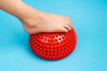 children's feet with a red balancer on a light blue background, treatment and prevention of flat...