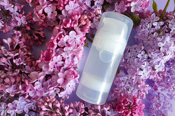 Water based lubricant. Transparent bottle of intimate lubricating gel and lilac flowers on purple...