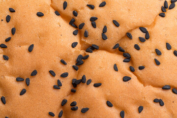 Closeup of nigella seeds on a wheat burger roll. Food background texture