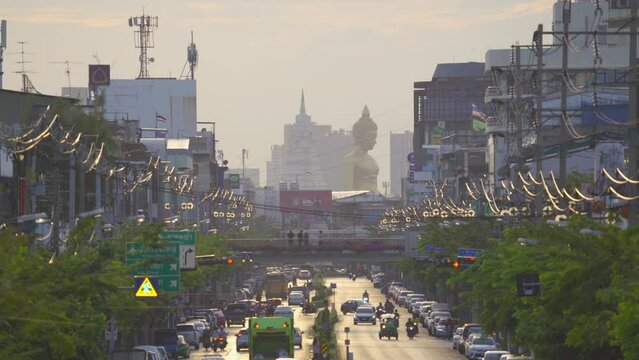 Aerial view of the Giant Golden Buddha in Wat Paknam Phasi Charoen Temple with cars on traffic street road in Phasi Charoen district, Bangkok. Urban town, Thailand. Downtown City.