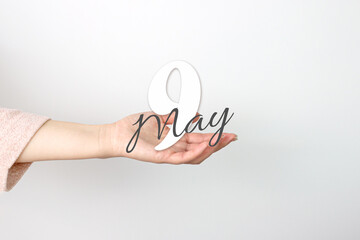 May 9th. Day 9 of month, Calendar date. Calendar Date floating over female hand on grey background....