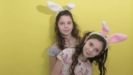 4k. Happy easter. Girls sisters celebrate easter. Cute girls sisters dressed as rabbits on yellow background. Spring holiday. Holiday bunny girls with long bunny ears. Easter activities for children - Powered by Adobe