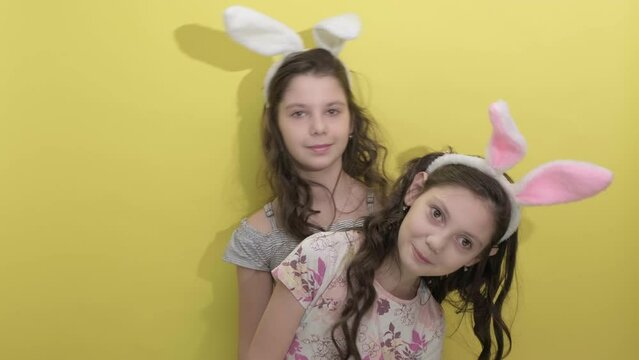 4k. Happy easter. Girls sisters celebrate easter. Cute girls sisters dressed as rabbits on yellow background. Spring holiday. Holiday bunny girls with long bunny ears. Easter activities for children