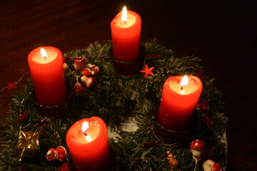 Adventskranz am vierten Advent mit 4 brennenden roten Kerzen