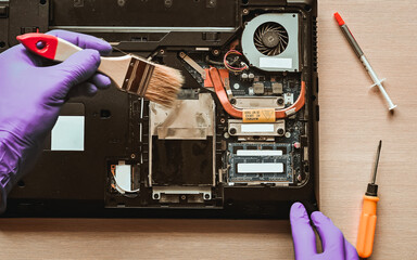 repair, maintenance of laptops. removing dust with a brush. hands in the frame
