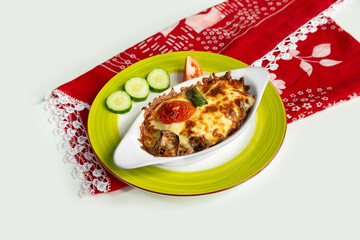 Greek dish moussaka with salad in a dish isolated on colorful table cloth top view on grey background