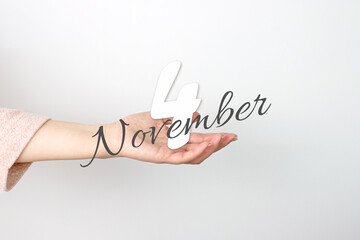 November 4th. Day 4 of month, Calendar date. Calendar Date floating over female hand on grey background. Autumn month, day of the year concept.