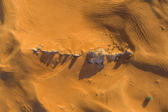 Aerial view of rock formation among sand dunes in the desert at sunset, Sharjah, Dubai, United Arab Emirates.