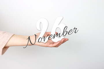 November 26th. Day 26 of month, Calendar date. Calendar Date floating over female hand on grey background. Autumn month, day of the year concept.