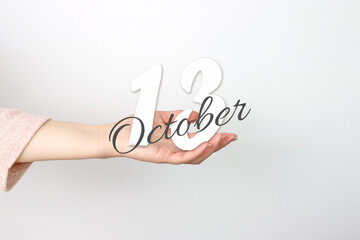 October 13rd. Day 13 of month, Calendar date. Calendar Date floating over female hand on grey background. Autumn month, day of the year concept.