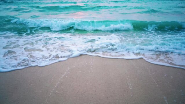 pan up reveal going from feet in slippers and foam and surf on white sand beach to blue waves and red tinged sunset dusk clouds in vijay nagar beach havelock andaman nicobar