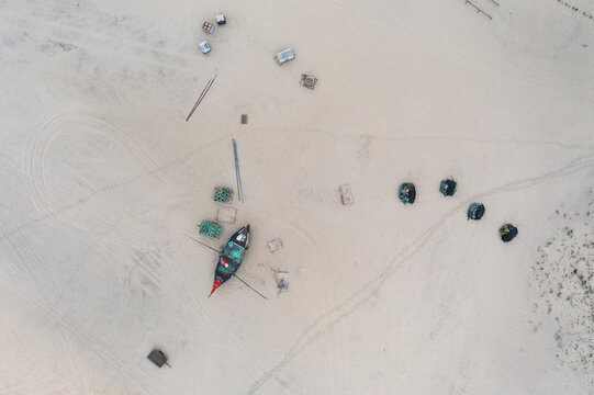 Aerial view of people along the shoreline prating the Arte Xavega, a Portuguese traditional fishing technique in Torreira, Portugal.