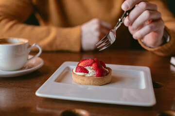 Man enjoying a delicious strawberry tart in a cafe.