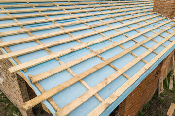 Aerial view of a brick house with wooden roof frame under construction.