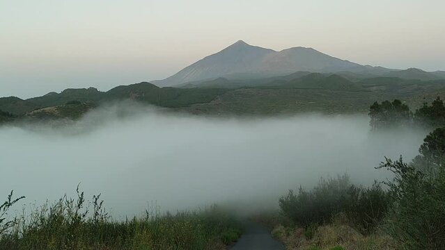 Breathtaking panoramic view of Mount Teide volcano rising above a dense sea of clouds at sunrise, tranquil mountain valley landscape in Tenerife, majestic wild nature travel destination background