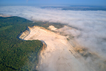 Aerial view of open pit mining site of limestone materials extraction for construction industry with excavators and dump trucks