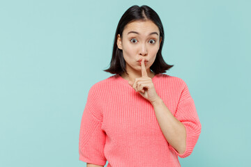 Young secret woman of Asian ethnicity 20s in pink sweater say hush be quiet with finger on lips...