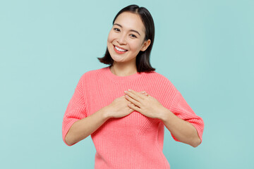 Young smiling kind-hearted happy woman of Asian ethnicity 20s in pink sweater put folded hands on...