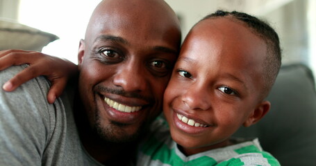 African father and child son together looking at cellphone screen