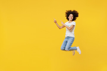 Full body young woman of African American ethnicity wears white volunteer t-shirt jump high point...