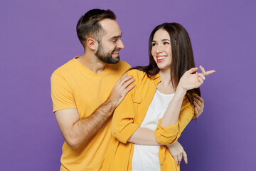 Young smiling happy lovely couple two friends family man woman 20s together wearing yellow casual clothes looking to each other hud cuddle isolated on plain violet color background studio portrait