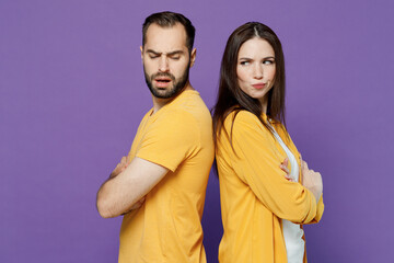 Obraz premium Young side profile view frowning offended sad couple two friends family man woman 20s together wearing yellow casual clothes standing back to back isolated on plain violet background studio portrait.