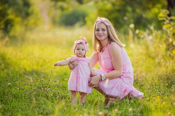 Fototapeta premium mother and daughter in identical pink dresses in nature