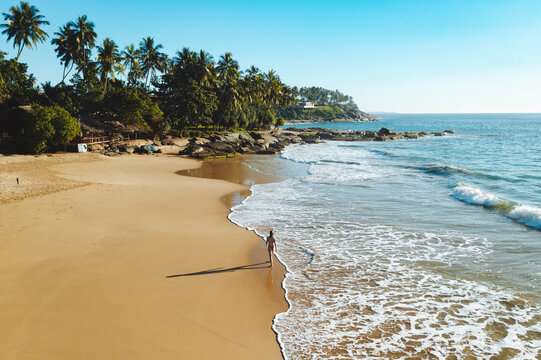 Aerial view of woman walking along the beach in Tangalle, Sri Lanka.