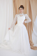 Fototapeta premium girl in a white wedding retro dress. wedding dress and hairstyle in the style of the 90's. Studio photo shoot in my mother's wedding dress. Bride photo shoot in the studio