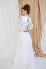 Fototapeta premium girl in a white wedding retro dress. wedding dress and hairstyle in the style of the 90's. Studio photo shoot in my mother's wedding dress. Bride photo shoot in the studio