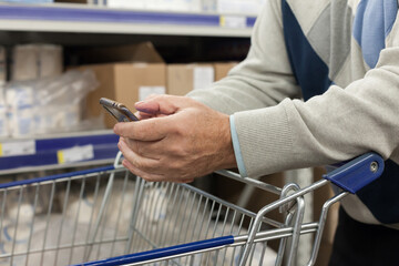 Senior  male customer with shopping basket in supermarket