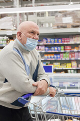 Senior   man wearing face mask shopping in supermarket