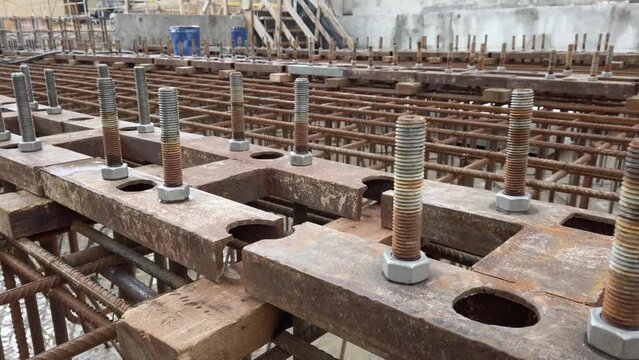 Framework of reinforced concrete foundation with metal anchor bolts designed for the installation of metal structures. Foundation of industrial building. Rows of anchor bolts and grid of metal rebars