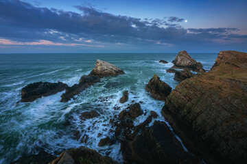 Stunning view of the sea cliffs by moonlight on the northern Scottish coast and rough seas. Famous rock formation on the Moray Coast, Scottish Highlands, Scotland