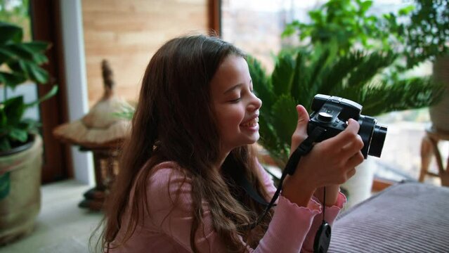 Little girl taking pictures with camera at home.