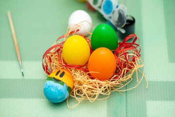 A girls in hare ears paints eggs. Easter. She is at home in the kitchen. Preparation for the holiday.