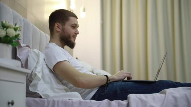 young man at home on the couch talking by video with a laptop.