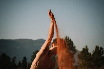 Young dancer performing and playing with red sand ground in the mountains