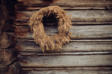 Stylish autumn rustic wreath on wooden wall. Creative boho wreath with dry grass