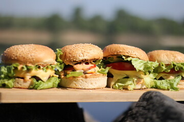 Homemade juicy burger in nature. Hamburger on a plate.